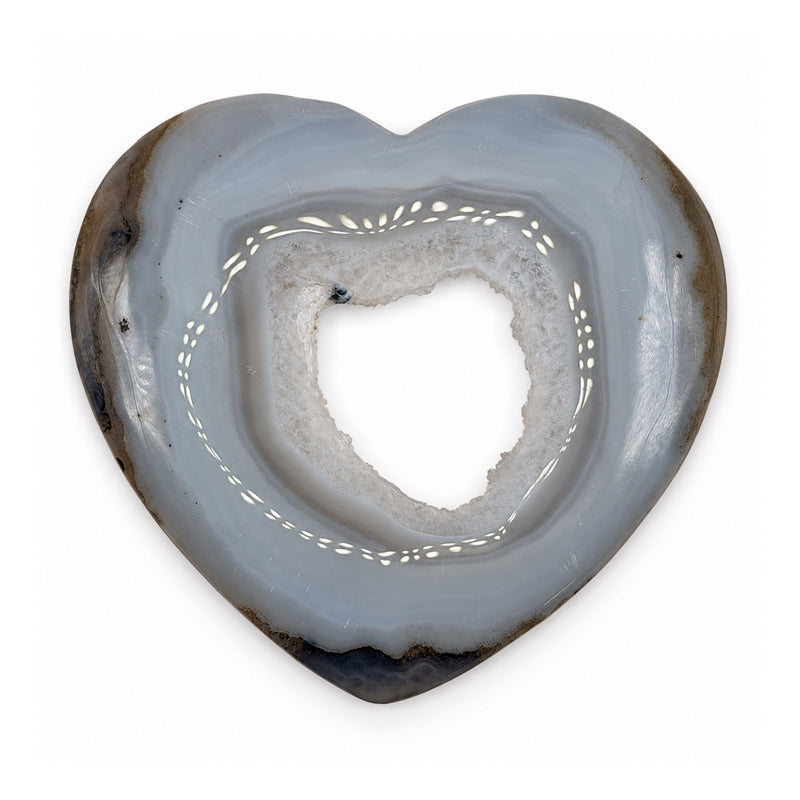 Front of a gray-blue stone heart with layered bands, a crystal-lined opening, and a dark outer edge.