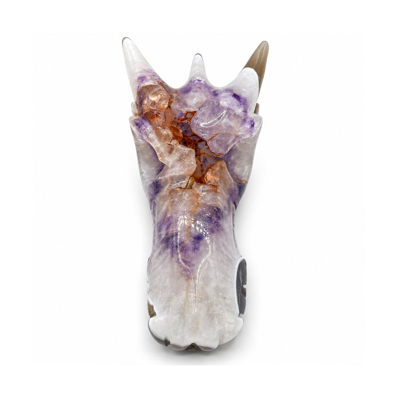 Elevated front view of a polished stone dragon skull, showing three horns, lavender zones and orange veins along the forehead.
