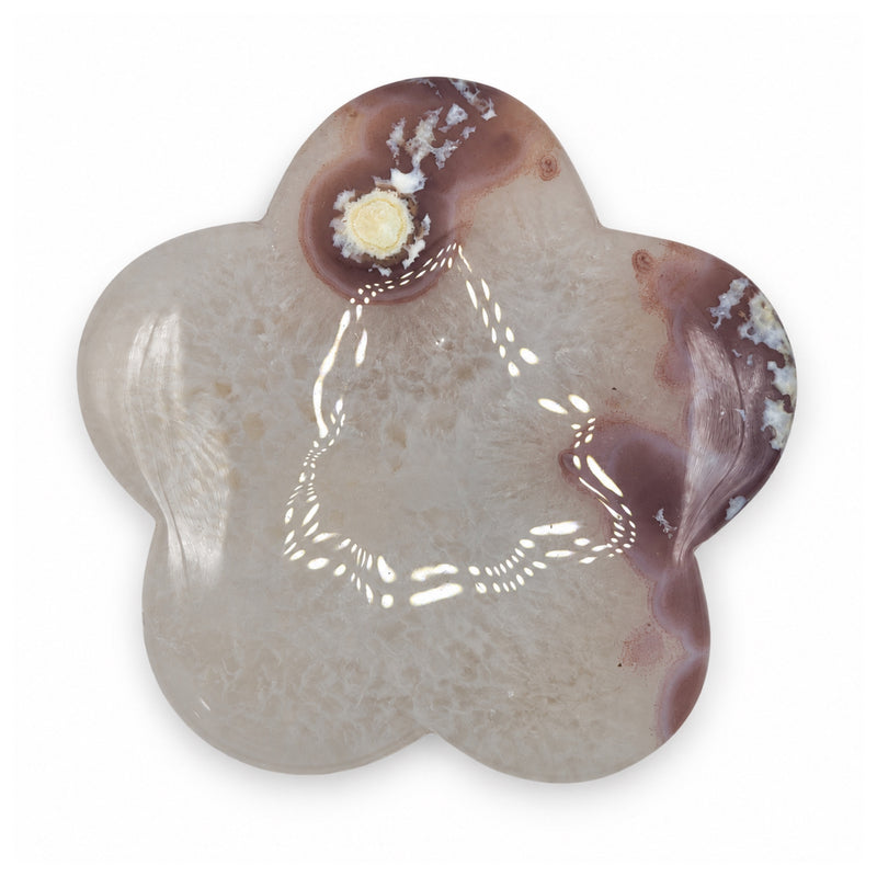 Opposite face of a pale flower-shaped stone with pink-brown patches, cloudy texture, and a small cream-yellow circular inclusion.
