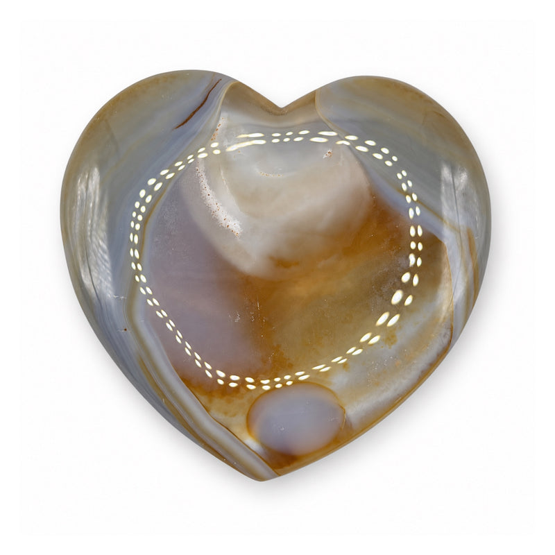 Reverse of a polished stone heart with gray-blue bands, amber-brown areas, and a pale oval near the tip.
