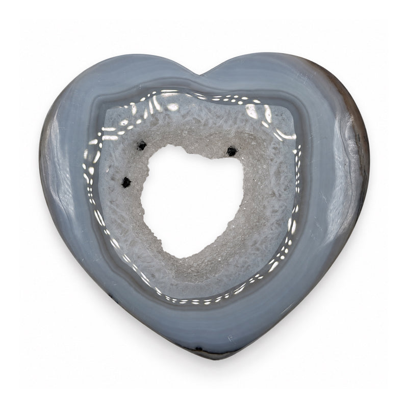 Reverse of a gray-blue stone heart showing an open crystalline center and three dark mineral inclusions.