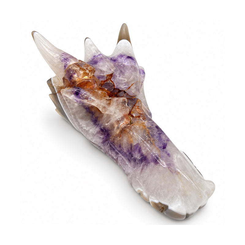 Front three-quarter view of a white and lavender stone dragon skull with orange mineral inclusions and the snout pointing right.