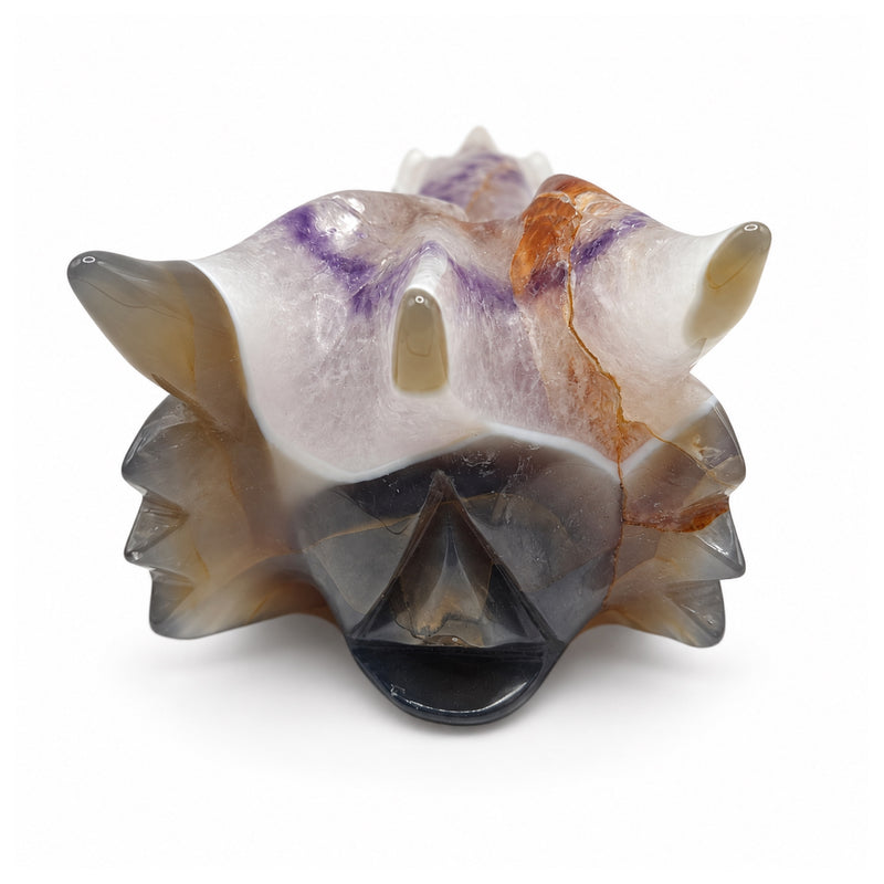 Direct rear view of a polished dragon skull carving, showing three horns, white and lavender stone, and smoky gray and brown bands.