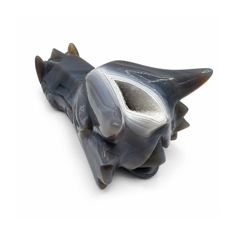 Rear three-quarter view of a gray stone dragon head showing its white crystal-lined cavity, layered pale bands, and curved horns.