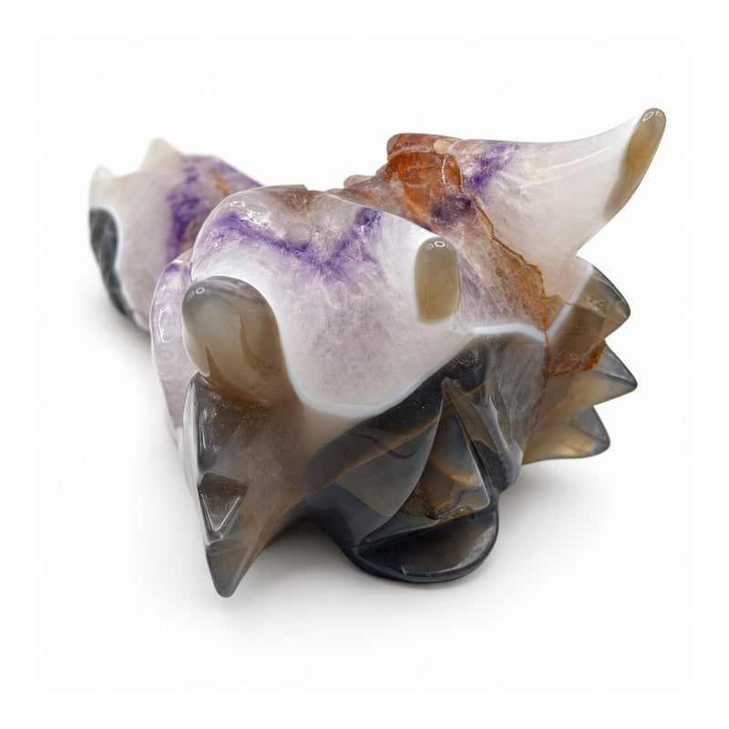 Opposite rear three-quarter view of a stone dragon skull, showing smoky horn tips, lavender areas, orange veins and carved rear spikes.
